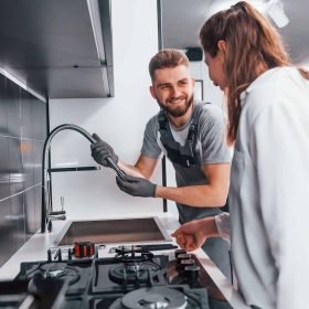 young-professional-plumber-in-grey-uniform-shows-results-of-work-for-housewife-on-the-kitchen.jpg young-professional-plumber-in-grey-uniform-shows-results-of-work-for-housewife-on-the-kitchen.jpg